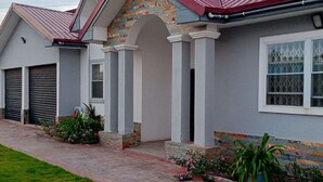 A two-story house with a red roof, a brick archway, and a front garage. - 4 Bedrooms Family House Sakumono (Sakumono)