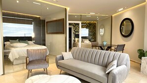 A modern hotel room with a bed, a sofa, a dining table, and a mirror. - santa clara 27 (Torremolinos)