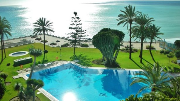 A swimming pool surrounded by palm trees and a view of the ocean. - santa clara 27 (Torremolinos)