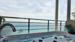 A bathtub with rose petals, a view of the ocean, and a balcony railing. - santa clara 27 (Torremolinos)