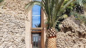 A hotel entrance with a stone facade, a palm tree, and a modern building in the background. - santa clara 27 (Torremolinos)