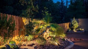 Ein angelegter Garten mit verschiedenen Pflanzen, einem Holzzaun und einer kleinen Dinosaurierstatue.