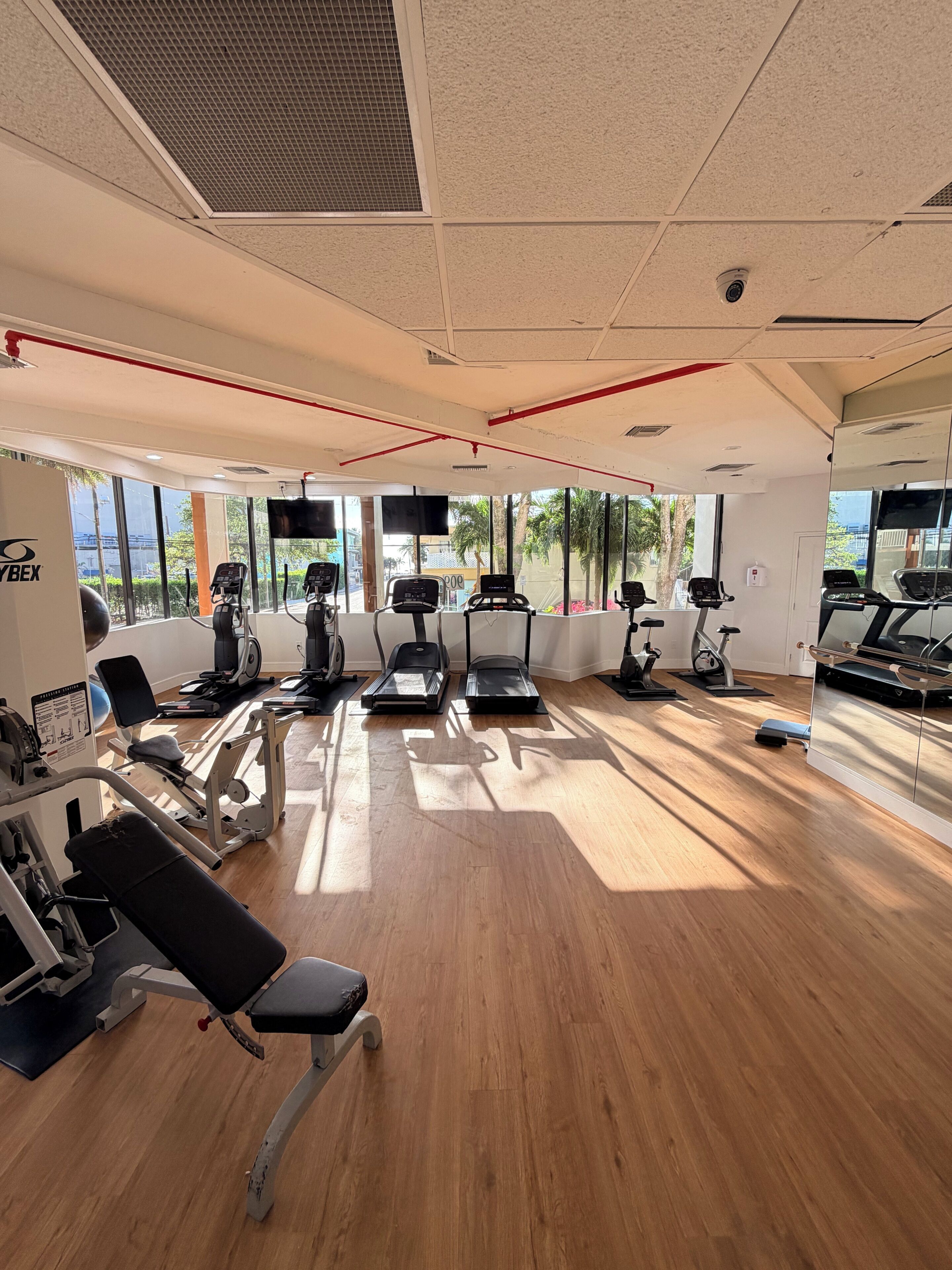 Un gimnasio con cintas de correr, elípticas y equipo de pesas.