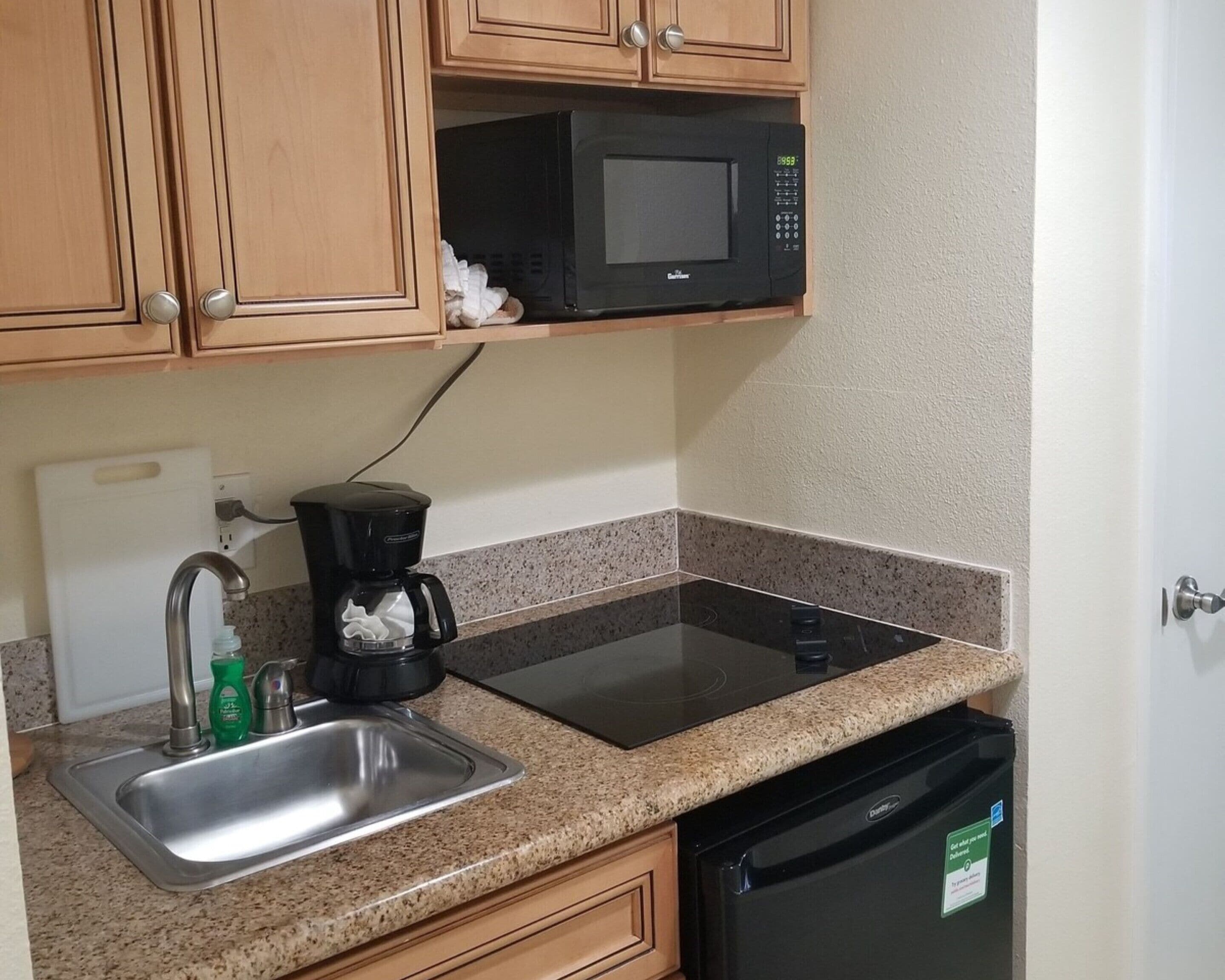 A kitchen with a microwave, coffee maker, sink, and dishwasher.