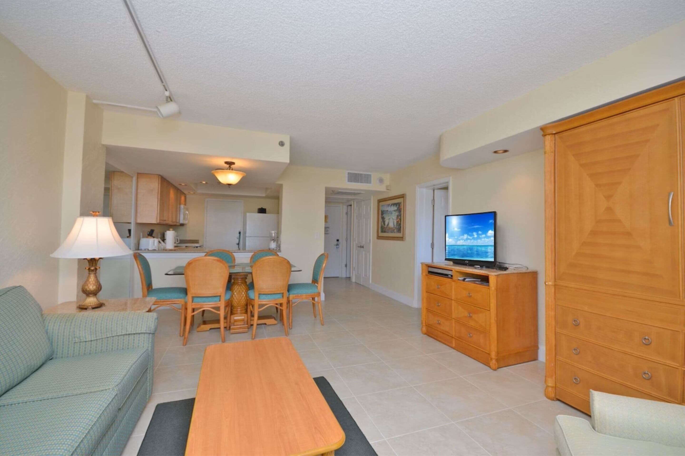 A living room with a sofa, a coffee table, a TV, and a dining area with chairs and a table.