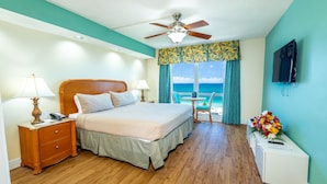 Ein Hotelzimmer mit Bett, Schreibtisch, Stuhl, Deckenventilator und Meerblick.