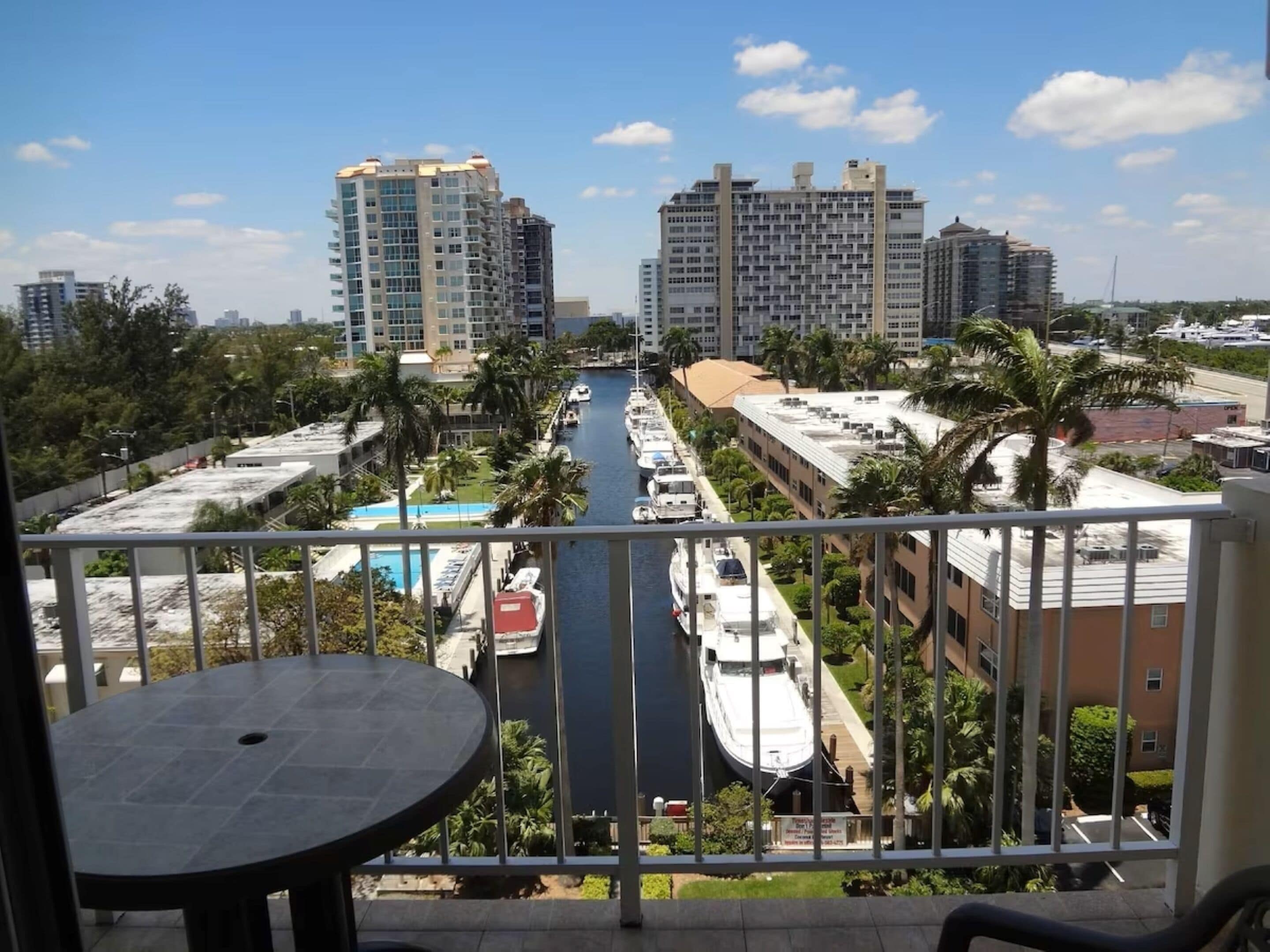 Un balcon avec vue sur un port de plaisance, de grands immeubles et une piscine.