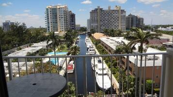 Uma varanda com vista para uma marina, edifícios altos e uma piscina.