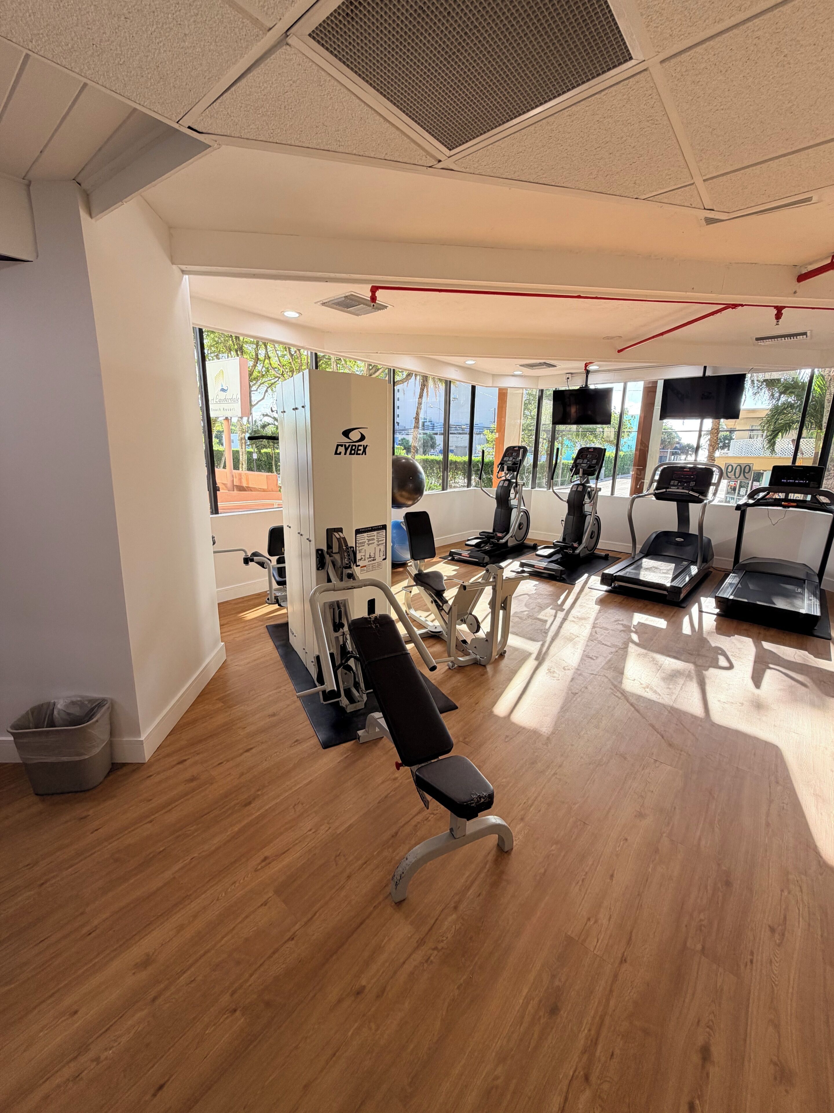 A gym with cardio machines, weight stations, and a bench.