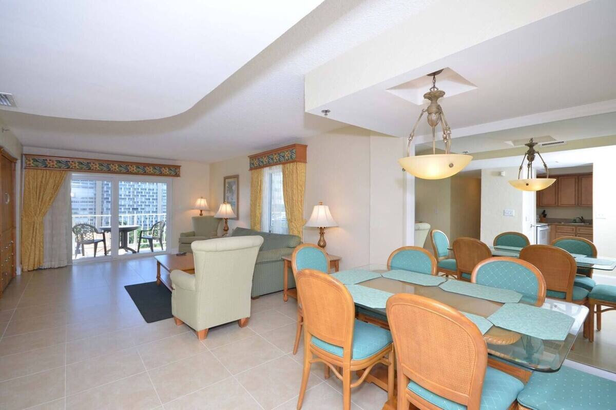 Un salón espacioso con comedor, que incluye una mesa grande y sillas, un sofá, y vistas al exterior.