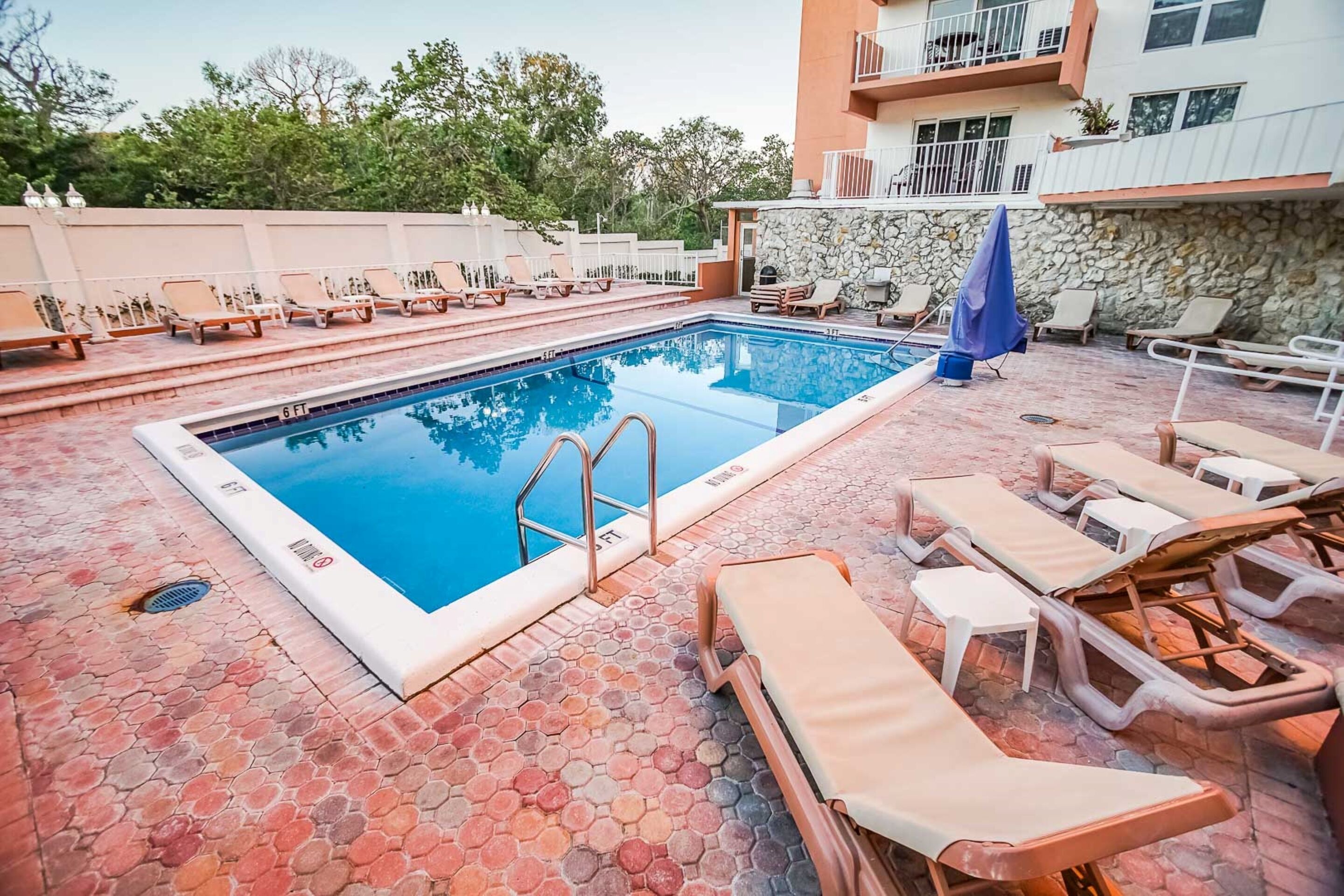 Una piscina con sillones de descanso y un muro de piedra.