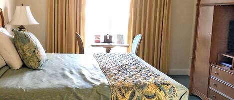 A hotel room with a bed, a table with a lamp, and a wardrobe.