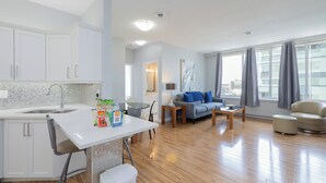 Une cuisine moderne avec des meubles blancs, un évier et un coin repas comprenant une table et des chaises.