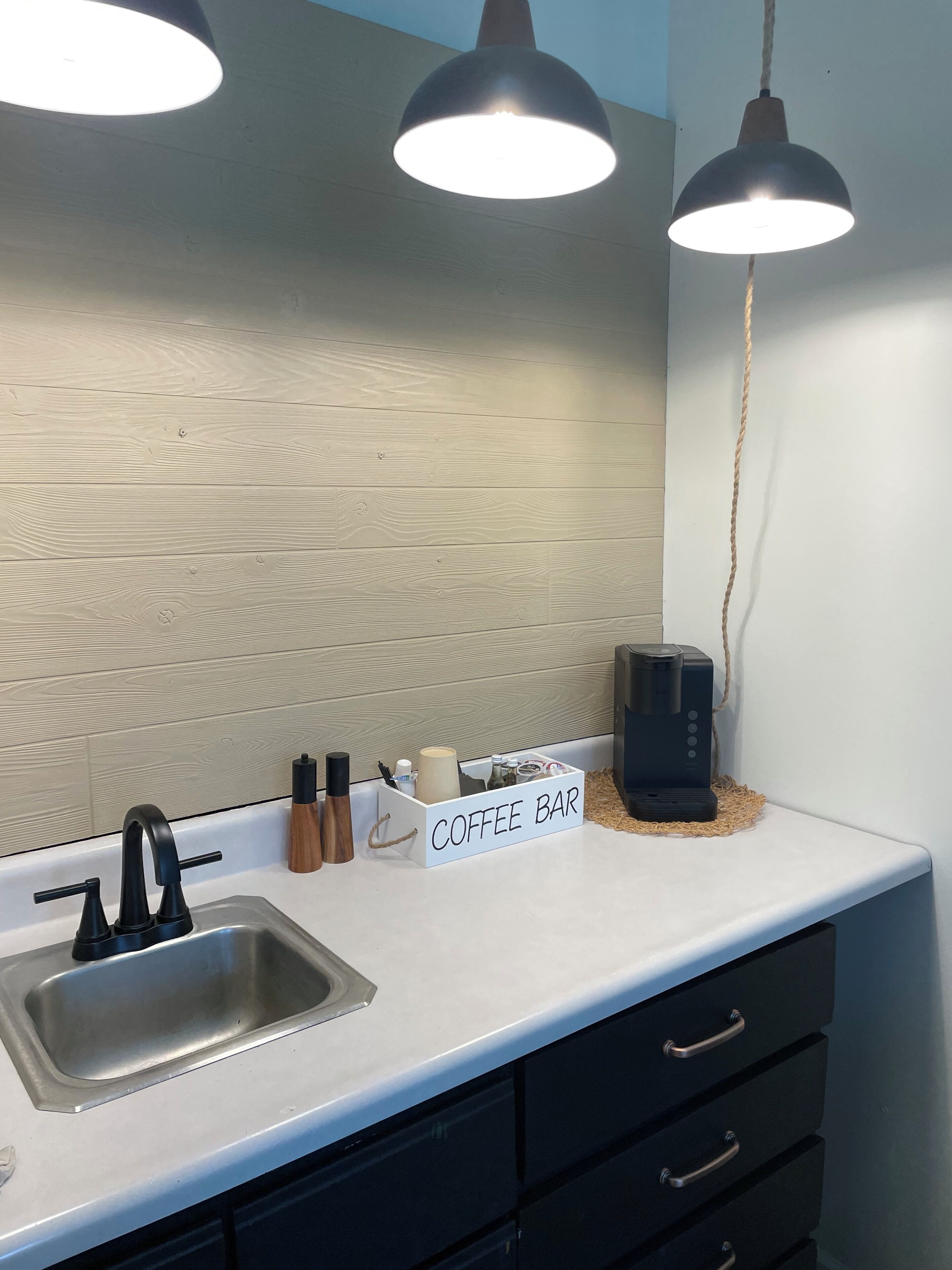 A kitchen with a coffee bar, a sink, and a coffee maker.