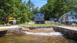 A house with a stone retaining wall and a small stream. - New House on Big Sebago w/ Private beach & dock! (Casco)