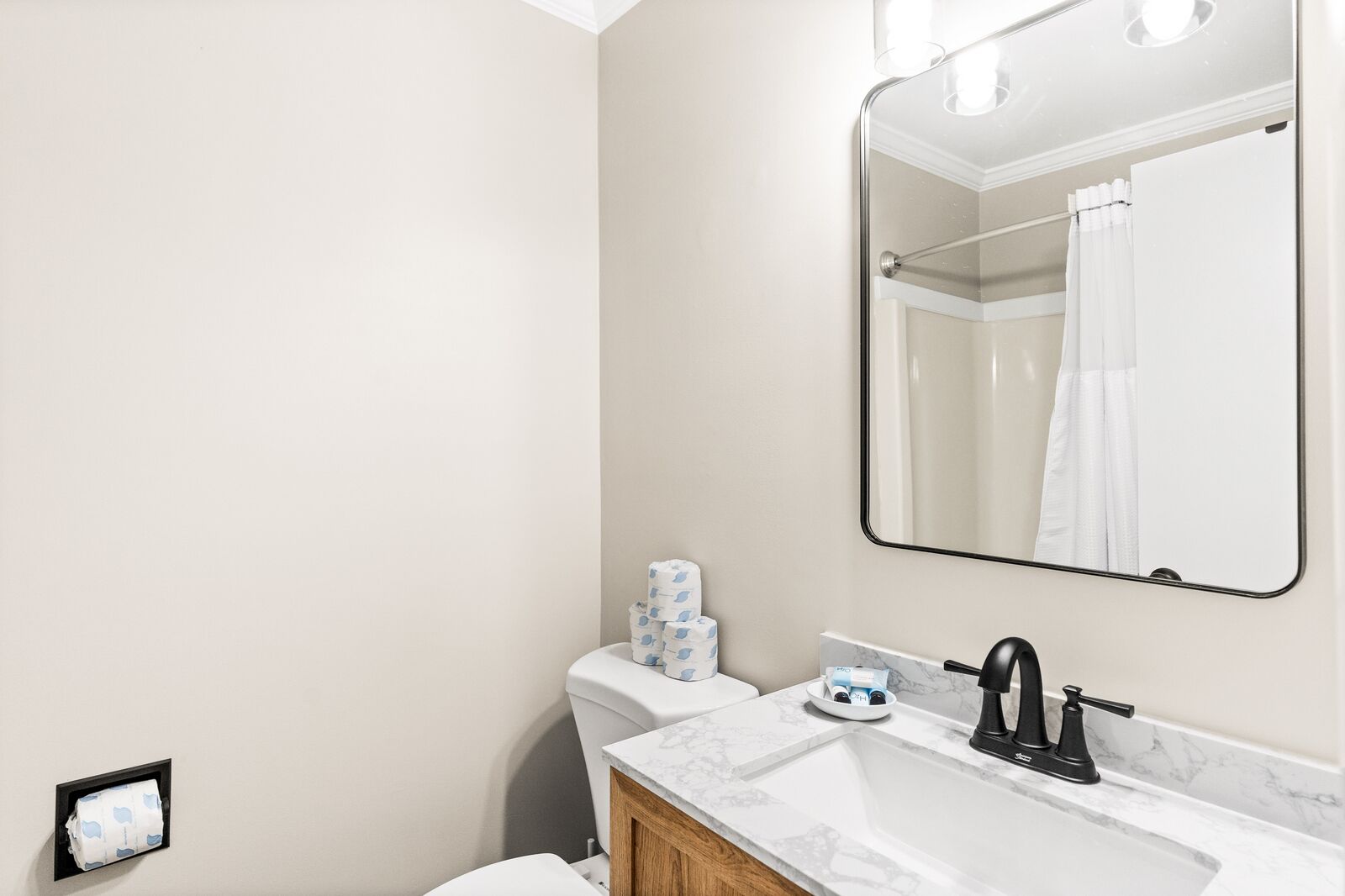 A bathroom with a toilet, sink, and mirror.