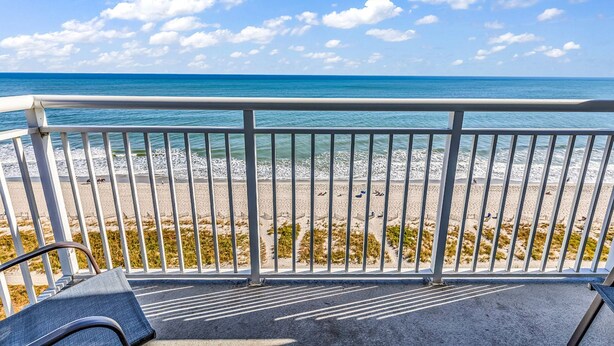 A balcony with a view of a beach and ocean.