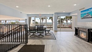 A hotel lobby with a fireplace, outdoor view, and a seating area with chairs and tables.