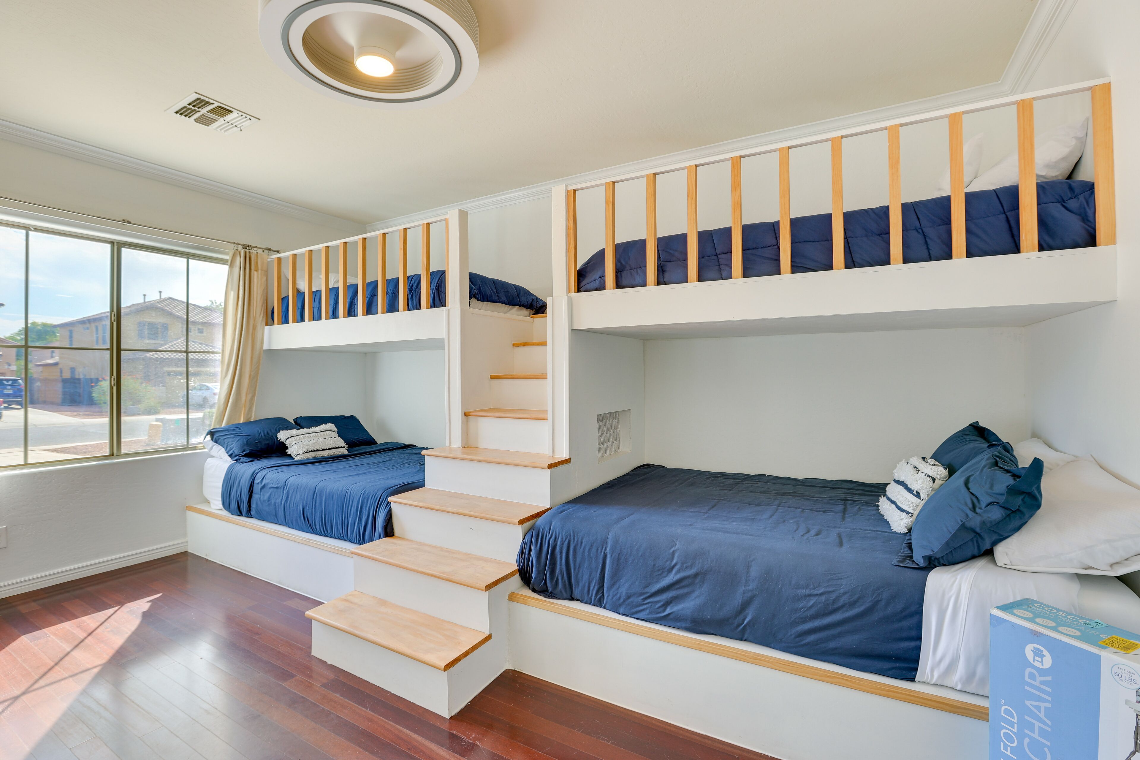 Una habitación con una cama litera, una silla plegable y una ventana con cortinas.