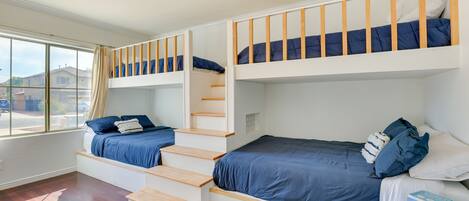 Una habitación con una cama litera, una silla plegable y una ventana con cortinas.