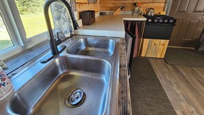 A kitchen with a stainless steel sink, wooden cabinets, and a stove.
