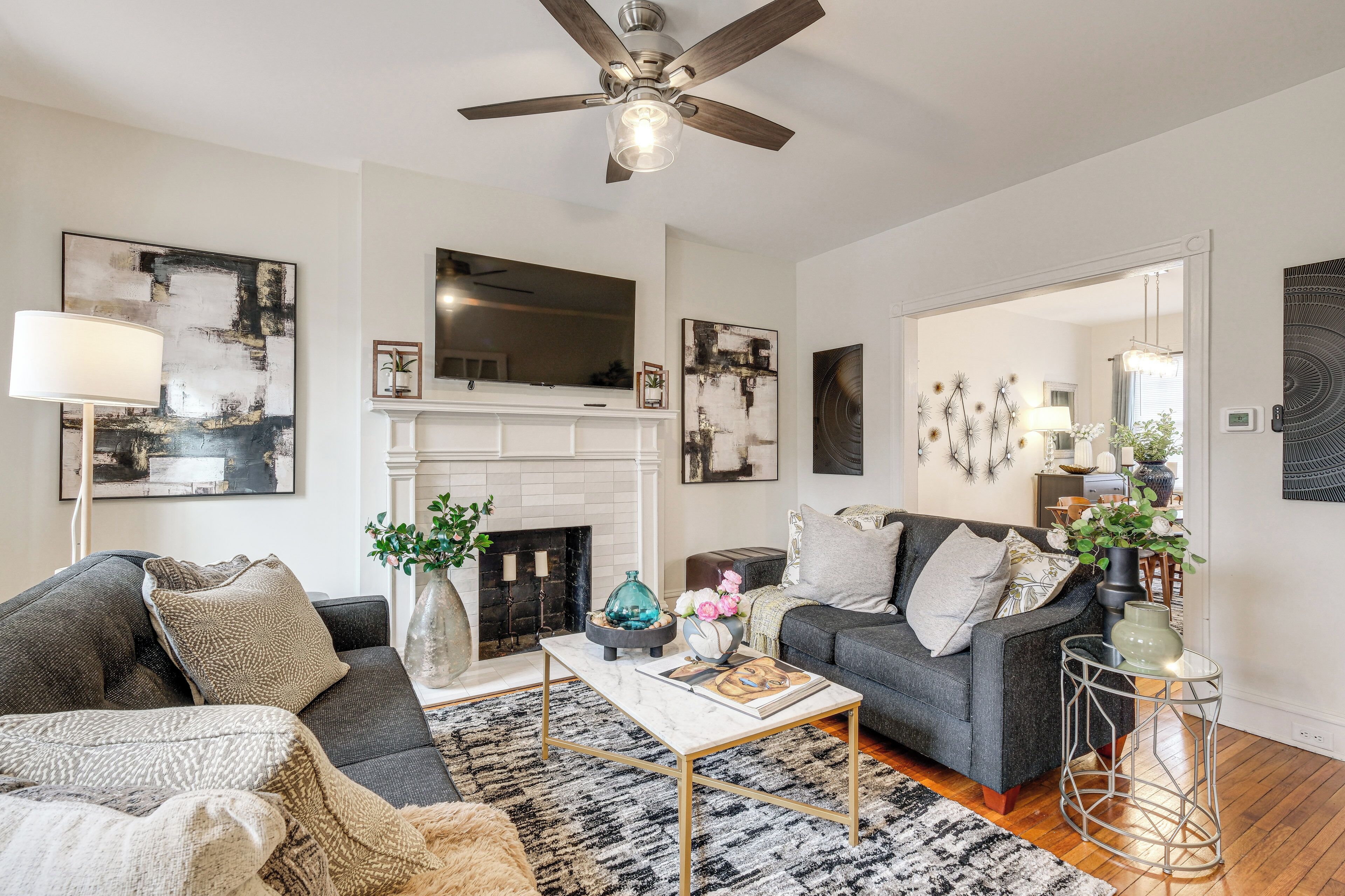 A modern living room with a fireplace, two sofas, a coffee table, and a ceiling fan.