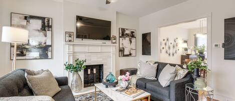 A modern living room with a fireplace, two sofas, a coffee table, and a ceiling fan.