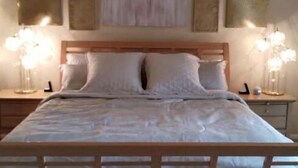 A bedroom with a wooden bed, white bedding, and two bedside lamps. - Westbury Townhome with community pool (Northglenn)