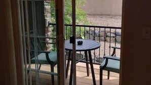 A sliding glass door leading to an outdoor patio with a round table and two chairs. - Westbury Townhome with community pool (Northglenn)