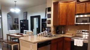 A modern kitchen with wooden cabinets, stainless steel appliances, and a central island. - Westbury Townhome with community pool (Northglenn)