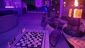 An outdoor seating area with a chess table, chairs, and a fire pit. - Buddy Ebson w/EV charger II (North Fort Myers)