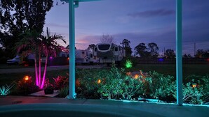 A covered outdoor area with a view of a recreational vehicle (RV) in the background. - Buddy Ebson w/EV charger II (North Fort Myers)