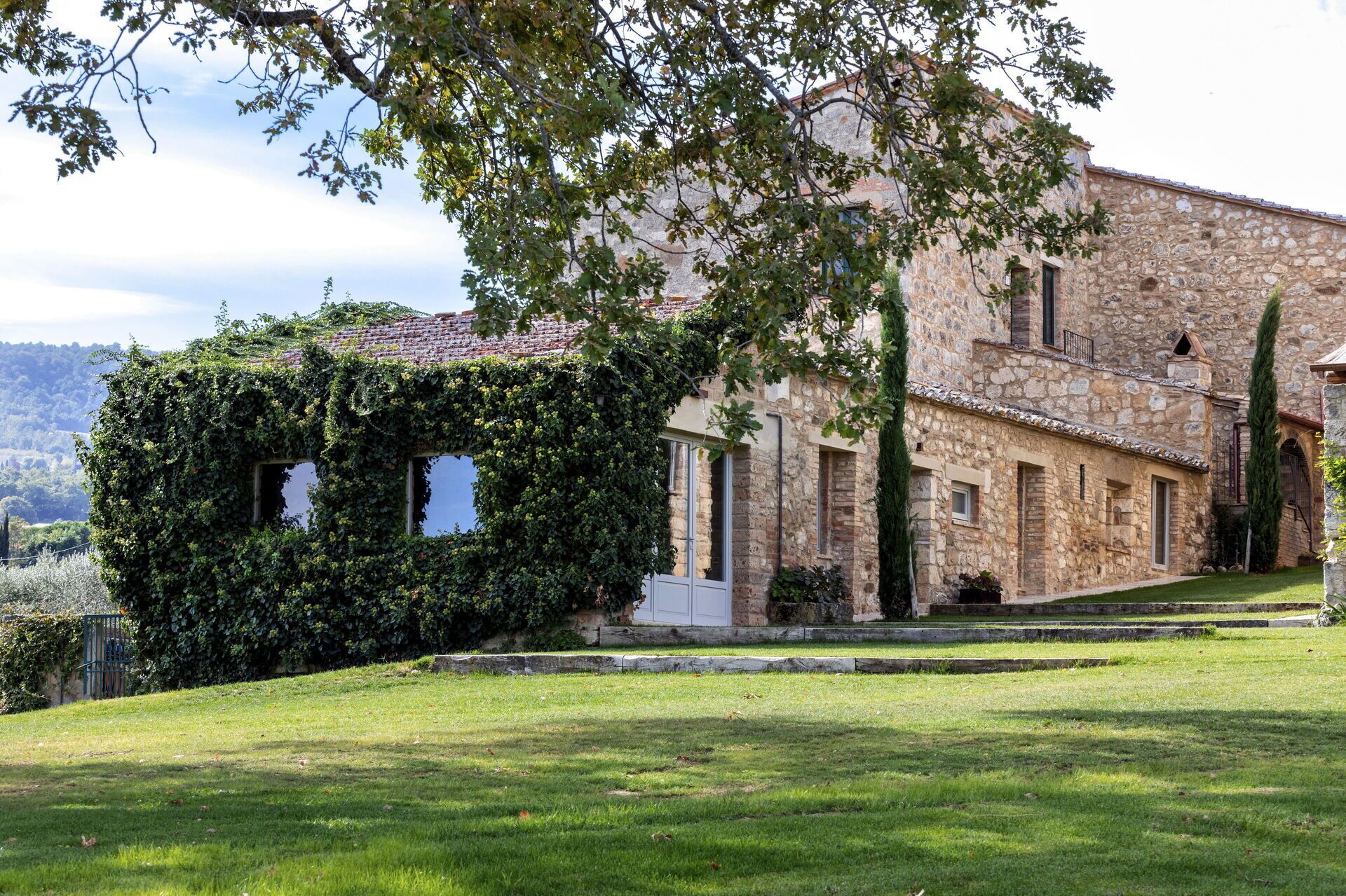 A stone building with ivy-covered walls and a grassy lawn.