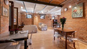 A cozy, well-lit room with a brick wall, a wooden table, a sofa, and a chair. - I Lauri 12, Emma Villas (Massignano)