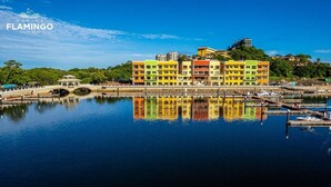 Um edifício colorido com várias varandas, uma ponte e um corpo d'água refletindo a construção.