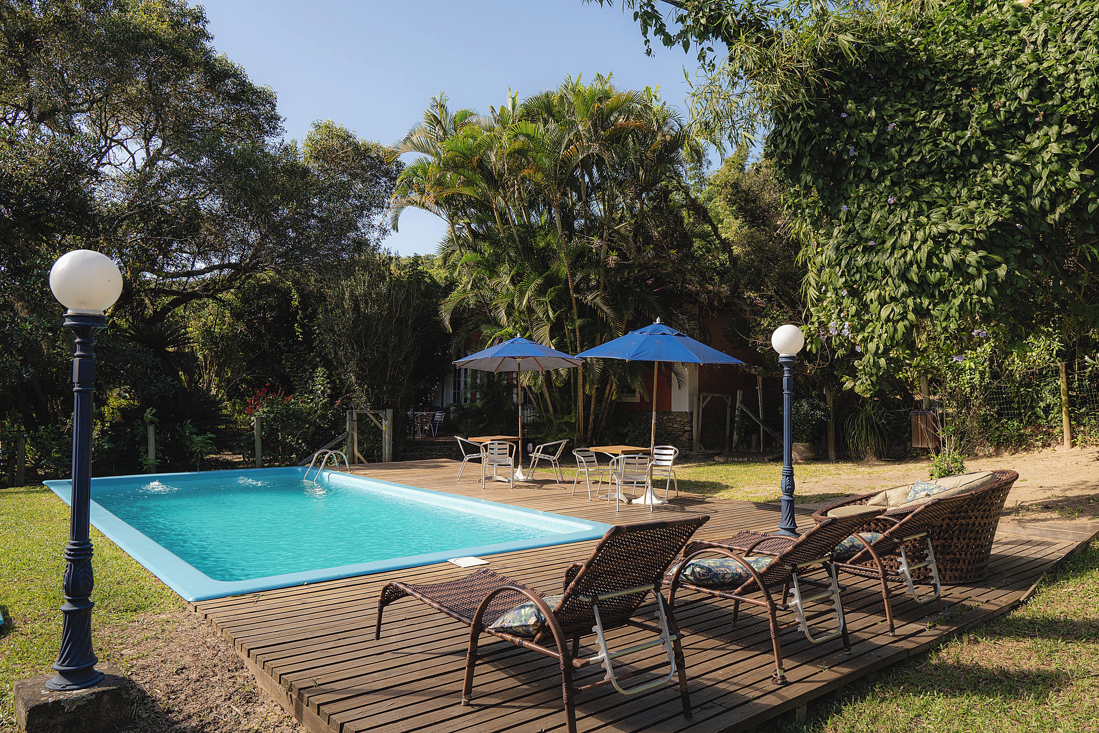 Una piscina al aire libre, sombrillas, sillones reclinables de piscina