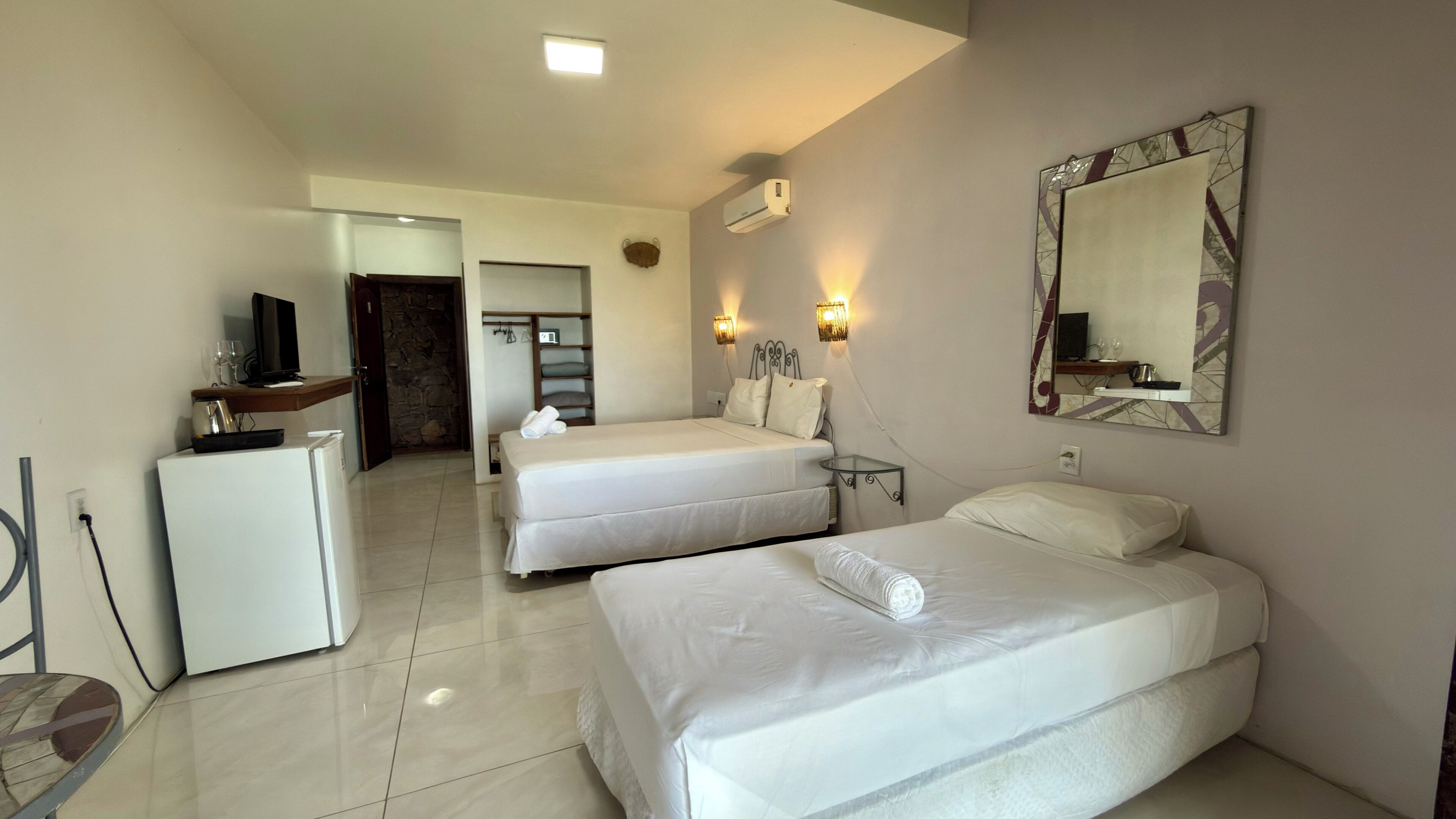 Une chambre d’hôtel avec deux lits, un bureau, un réfrigérateur et une télévision.