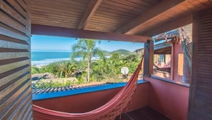 A hammock in a balcony with a view of the ocean and hills. - Pousada Villa Agrifóglio (Imbituba)