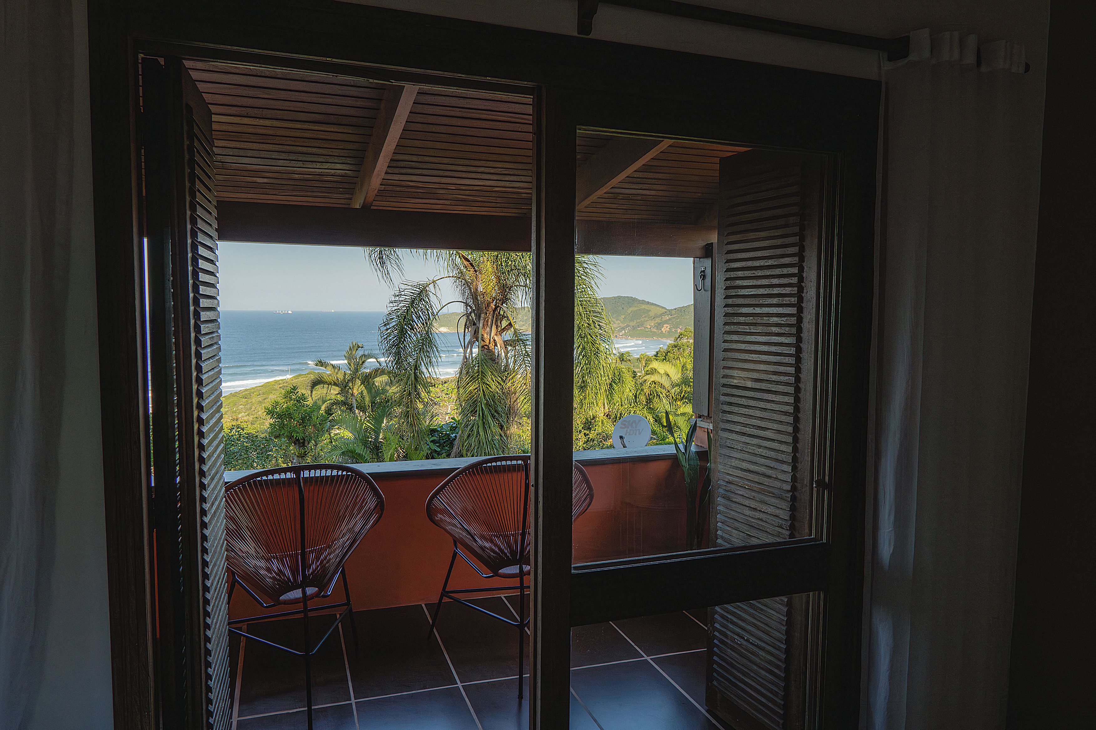A balcony with two chairs, a view of the ocean, and a sign indicating a TV channel.