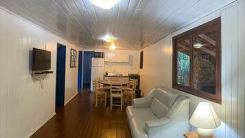 A compact living space with a dining area, a sofa, a TV, and a kitchen.