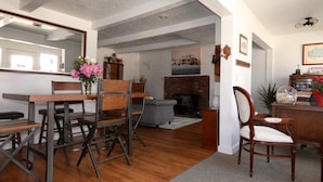 A dining area with a wooden table and chairs, a vase of flowers, and a brick fireplace. - The Idaho City Hotel (Idaho City)