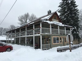 Una cabaña de dos pisos con balcón, rodeada de nieve.