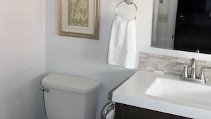 A bathroom with a toilet, a sink, and a framed picture on the wall. - The Idaho City Hotel (Idaho City)