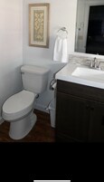 Un baño con inodoro, lavabo y un cuadro en la pared.