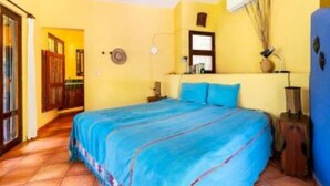 Un dormitorio con cama, mesita de noche, lámpara y una guitarra.