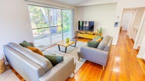 A modern living room with a sofa, armchair, coffee table, and a TV. - Kiali @ Cape Villas Dunsborough (Dunsborough)