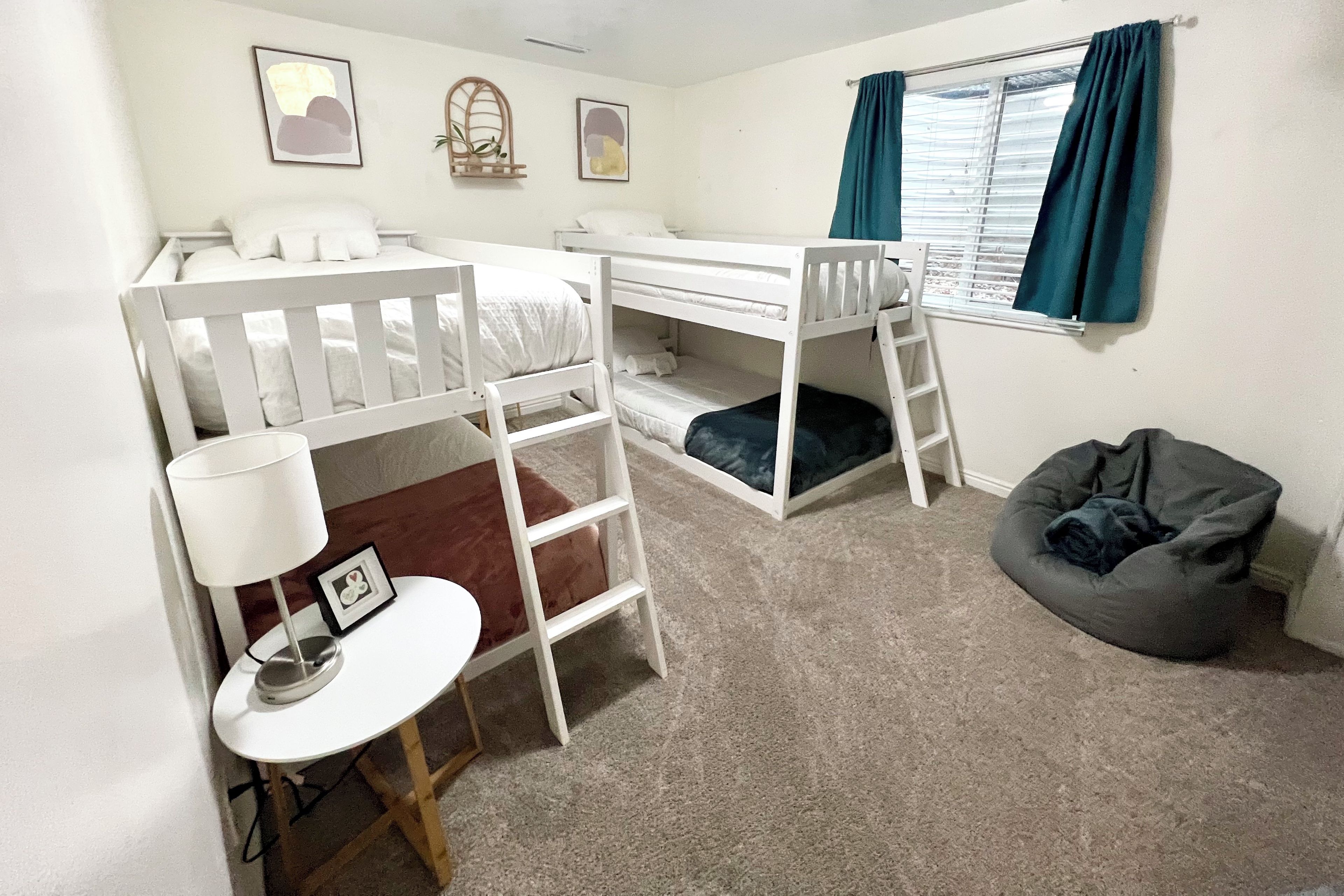A bunk bed room with a desk, chair, and bean bag.