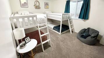 A bunk bed room with a desk, chair, and bean bag.