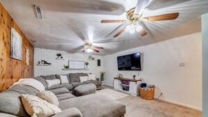 Una sala de estar con un sofá modular, un ventilador de techo, un televisor y una mesita auxiliar.