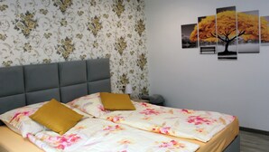 Una camera da letto con un letto, carta da parati floreale e tre quadri appesi al muro.
